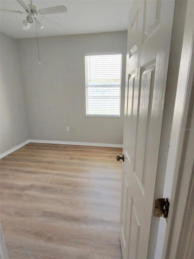 unfurnished room with ceiling fan, light wood-style flooring, and baseboards