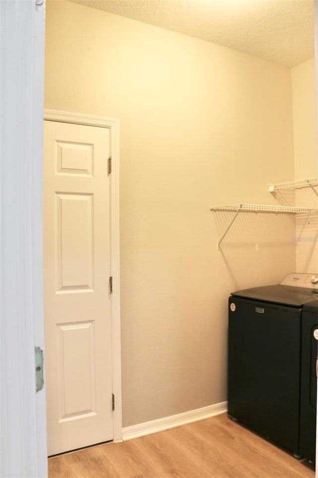 laundry room with washer / dryer, light wood-style flooring, laundry area, and baseboards