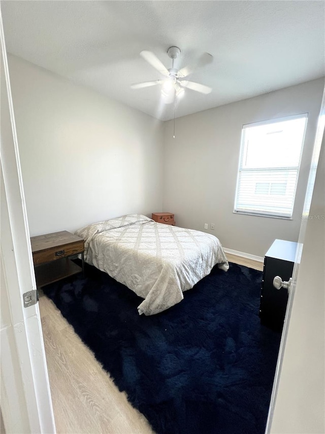 bedroom featuring ceiling fan, baseboards, and wood finished floors