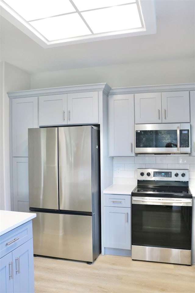 kitchen with tasteful backsplash, light wood-style flooring, appliances with stainless steel finishes, and light countertops