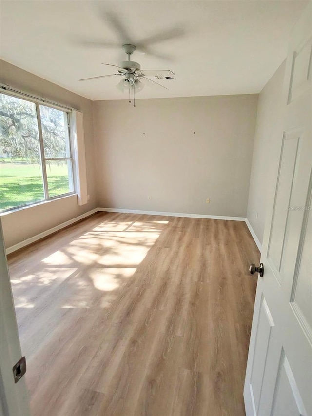 empty room featuring light wood-style flooring, baseboards, and ceiling fan