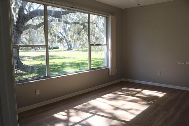 empty room with dark wood-type flooring and baseboards