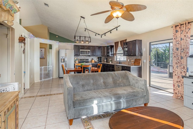 tiled living room featuring vaulted ceiling, sink, ceiling fan, and a textured ceiling