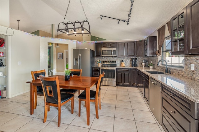 kitchen with appliances with stainless steel finishes, sink, dark brown cabinetry, and decorative light fixtures