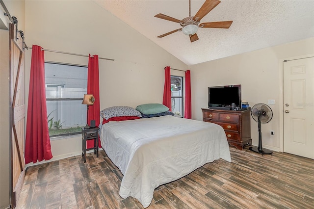 bedroom with lofted ceiling, ceiling fan, a textured ceiling, dark hardwood / wood-style flooring, and a barn door