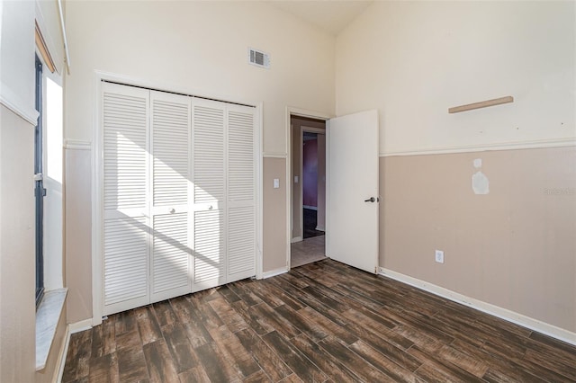 unfurnished room with dark wood-type flooring and a towering ceiling