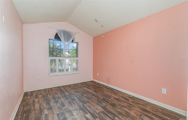 empty room featuring vaulted ceiling, dark wood-type flooring, and a textured ceiling