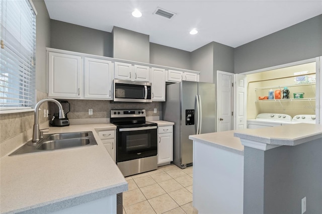 kitchen featuring sink, white cabinetry, washer and dryer, stainless steel appliances, and backsplash