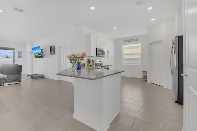 kitchen featuring sink, a breakfast bar area, appliances with stainless steel finishes, white cabinetry, and kitchen peninsula