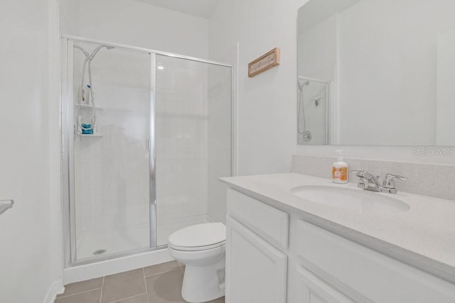 bathroom featuring tile patterned flooring, vanity, a shower with shower door, and toilet