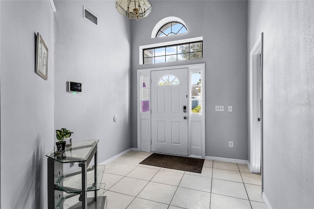 entryway featuring an inviting chandelier, light tile patterned floors, and a towering ceiling