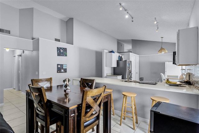 dining room with high vaulted ceiling, light tile patterned floors, and a textured ceiling