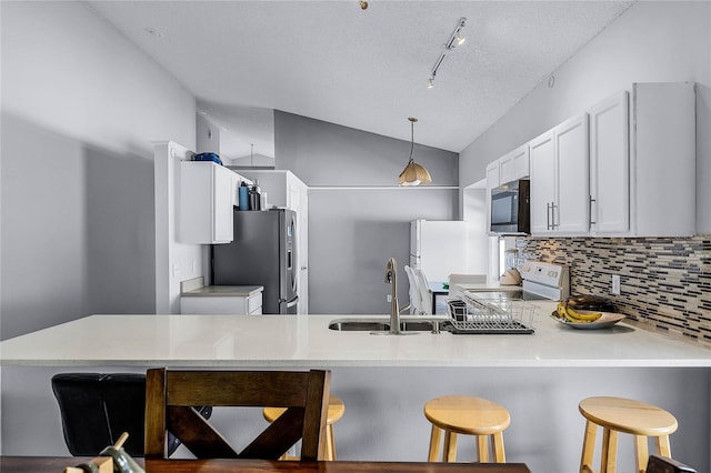 kitchen featuring a breakfast bar, sink, hanging light fixtures, kitchen peninsula, and white appliances