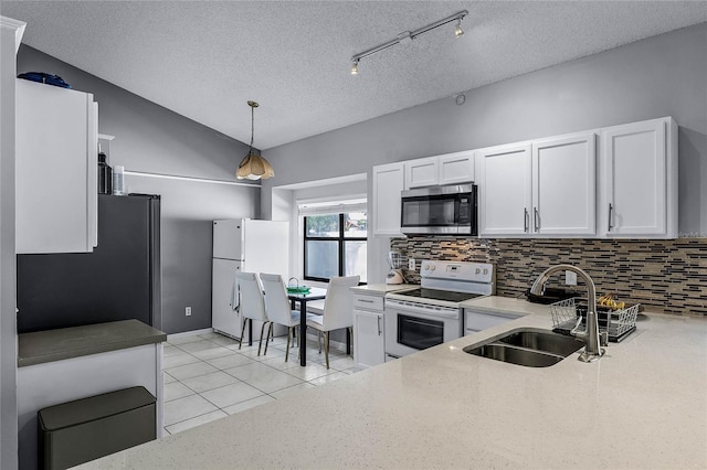 kitchen featuring vaulted ceiling, appliances with stainless steel finishes, decorative light fixtures, white cabinetry, and sink