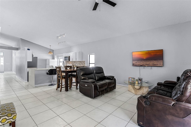 tiled living room with lofted ceiling, track lighting, and ceiling fan