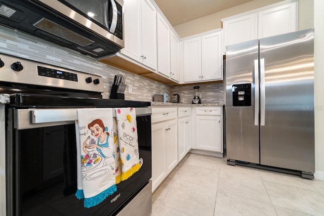 kitchen with light stone counters, light tile patterned floors, stainless steel appliances, decorative backsplash, and white cabinets