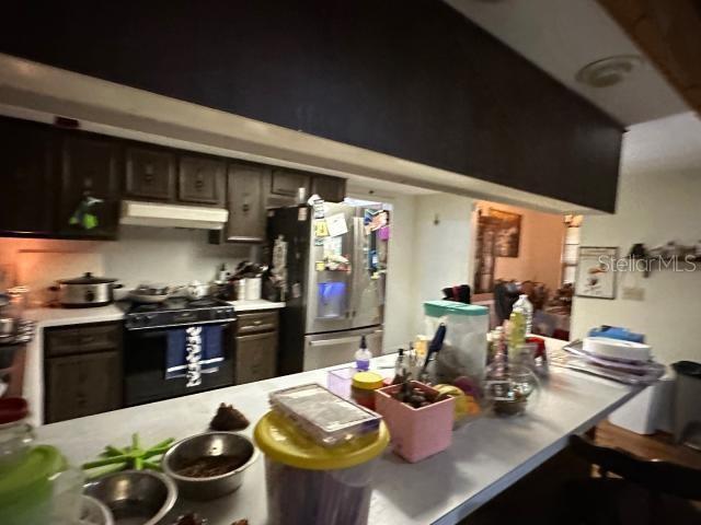 kitchen with stainless steel refrigerator, dark brown cabinetry, and black range with gas cooktop