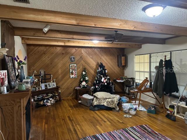 interior space featuring dark hardwood / wood-style flooring, beam ceiling, wooden walls, and a textured ceiling