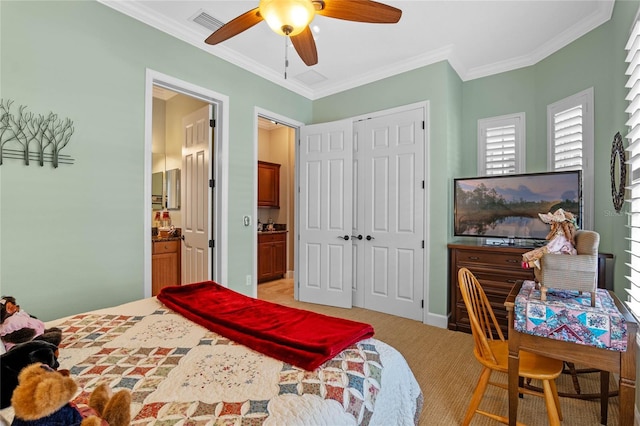 bedroom with crown molding, ensuite bath, ceiling fan, a closet, and light colored carpet