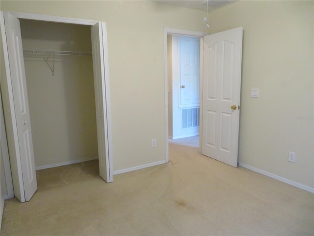 unfurnished bedroom featuring light colored carpet and a closet