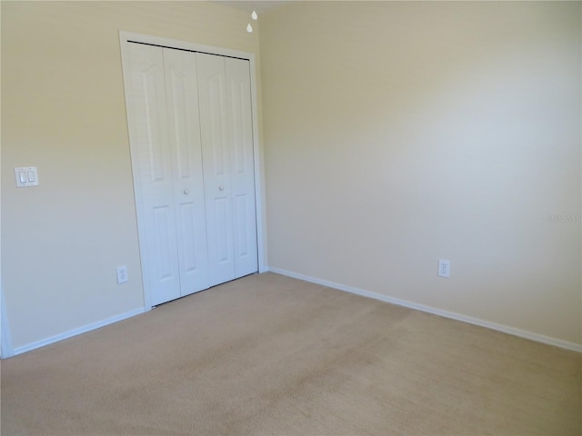 unfurnished bedroom featuring light colored carpet and a closet