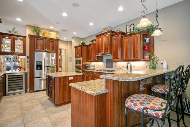 kitchen featuring wine cooler, pendant lighting, appliances with stainless steel finishes, a peninsula, and a kitchen breakfast bar