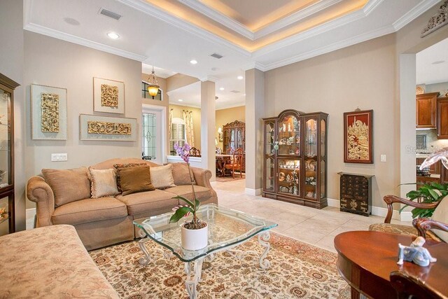 living room featuring light tile patterned floors, baseboards, visible vents, and ornamental molding