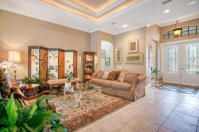 living area featuring french doors, light tile patterned floors, recessed lighting, a raised ceiling, and ornamental molding