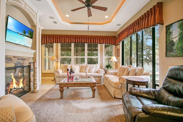 sunroom / solarium featuring ceiling fan, visible vents, a tray ceiling, and a stone fireplace