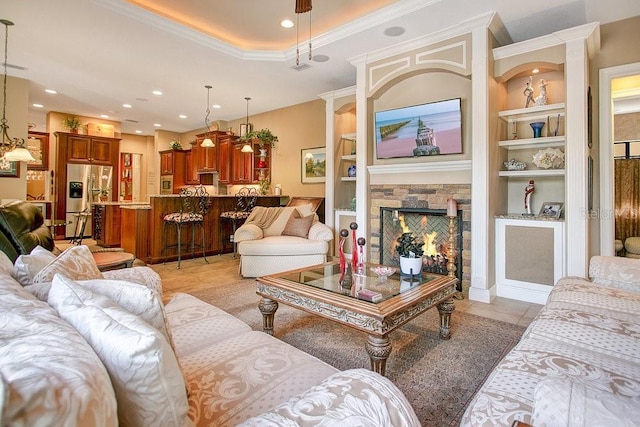 living room with built in shelves, a tray ceiling, a fireplace, and light tile patterned flooring