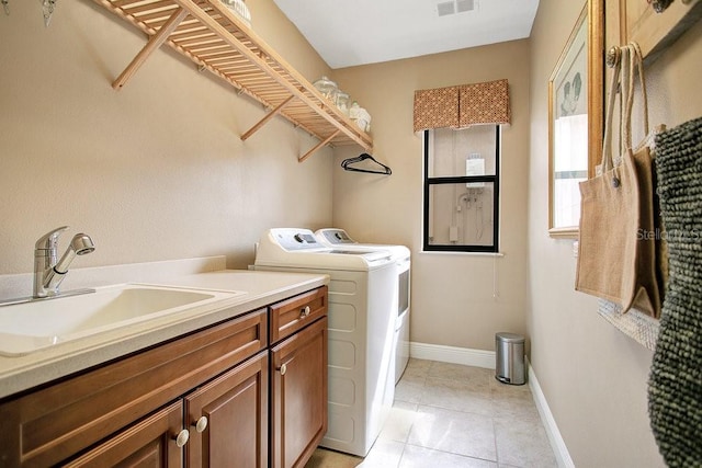 washroom with cabinet space, light tile patterned floors, baseboards, washer and clothes dryer, and a sink