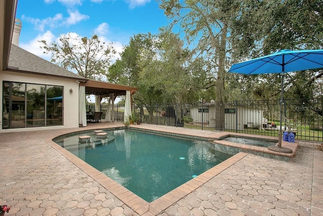 view of pool with a patio, fence, and a pool with connected hot tub