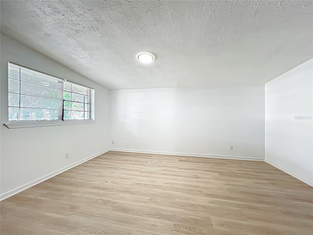 spare room with a textured ceiling and light wood-type flooring