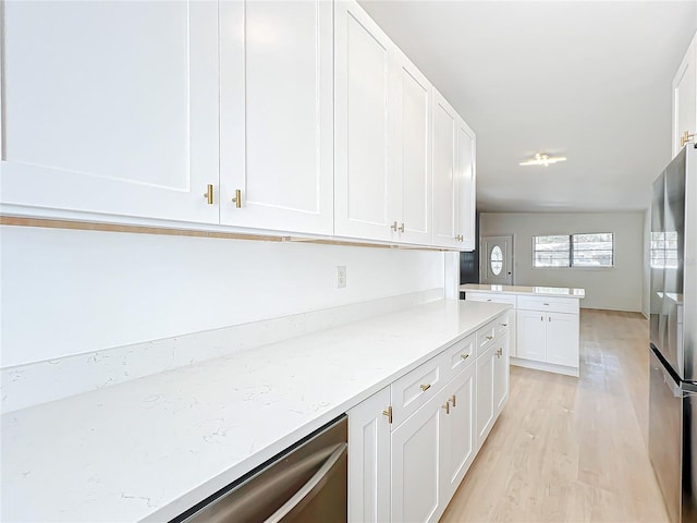 kitchen featuring white cabinetry, light stone counters, light wood-type flooring, and appliances with stainless steel finishes