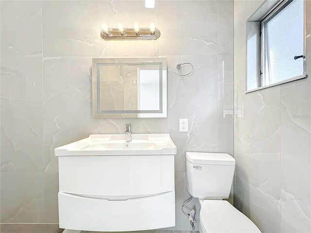 bathroom with vanity, tile walls, and toilet