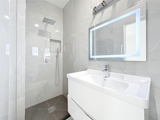 bathroom with vanity, tile patterned flooring, tile walls, and a shower