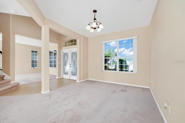 spare room featuring light colored carpet, an inviting chandelier, and french doors