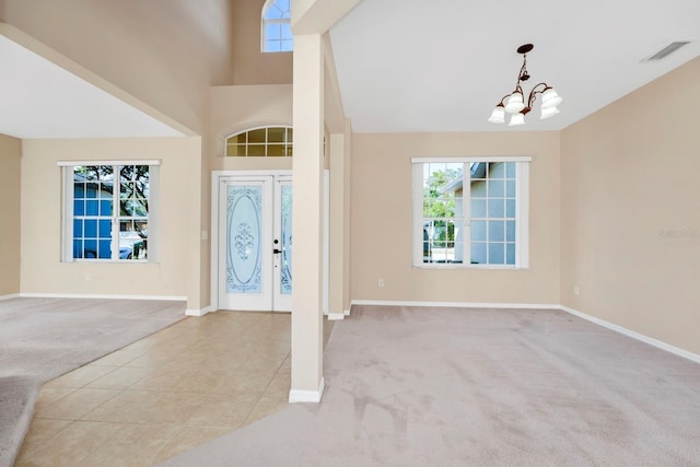 carpeted foyer entrance with a towering ceiling, an inviting chandelier, and french doors