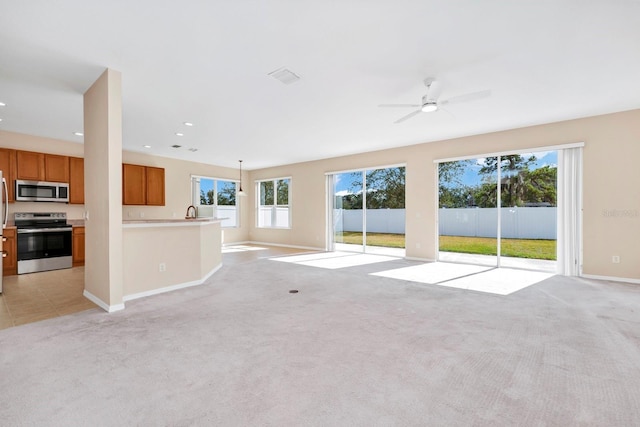 unfurnished living room featuring ceiling fan, light colored carpet, and sink