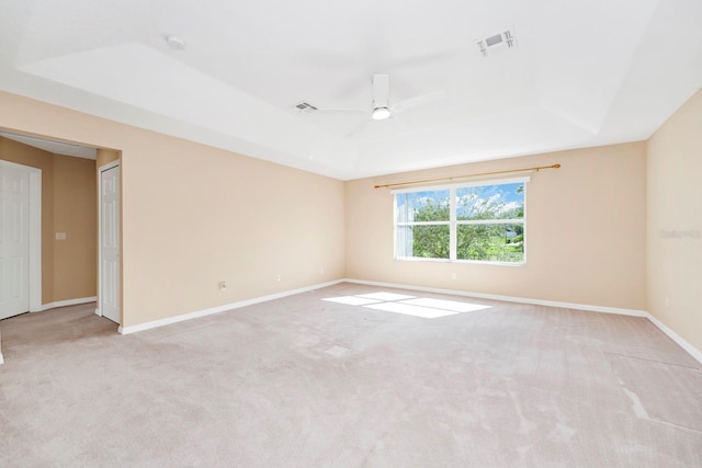 carpeted spare room with ceiling fan and a tray ceiling