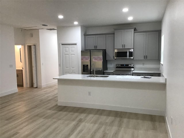 kitchen featuring appliances with stainless steel finishes, sink, light hardwood / wood-style floors, and gray cabinetry