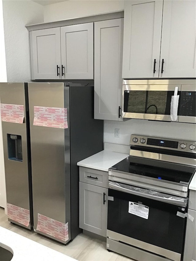 kitchen with gray cabinetry and appliances with stainless steel finishes