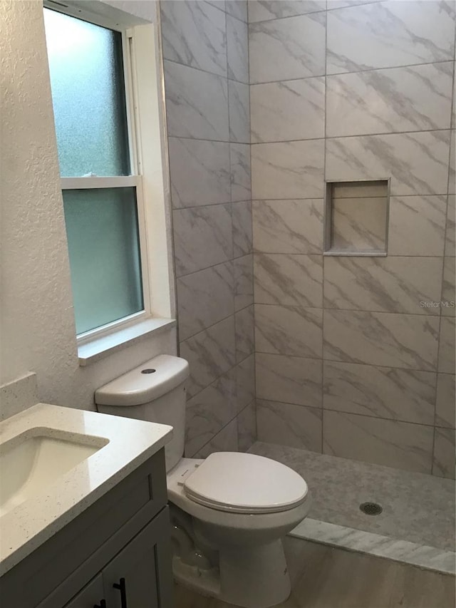 bathroom featuring vanity, toilet, and tiled shower