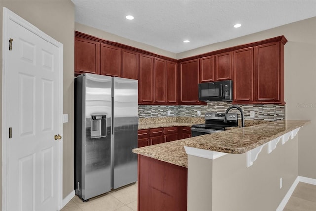 kitchen with a kitchen bar, tasteful backsplash, appliances with stainless steel finishes, kitchen peninsula, and light stone countertops