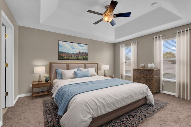 carpeted bedroom featuring a raised ceiling and ceiling fan