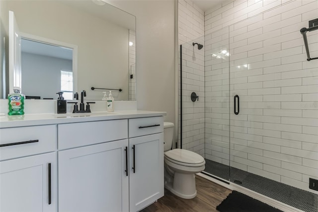 bathroom with hardwood / wood-style flooring, vanity, an enclosed shower, and toilet