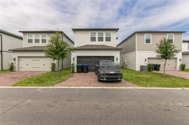 view of front of home featuring a garage, central air condition unit, and a front lawn