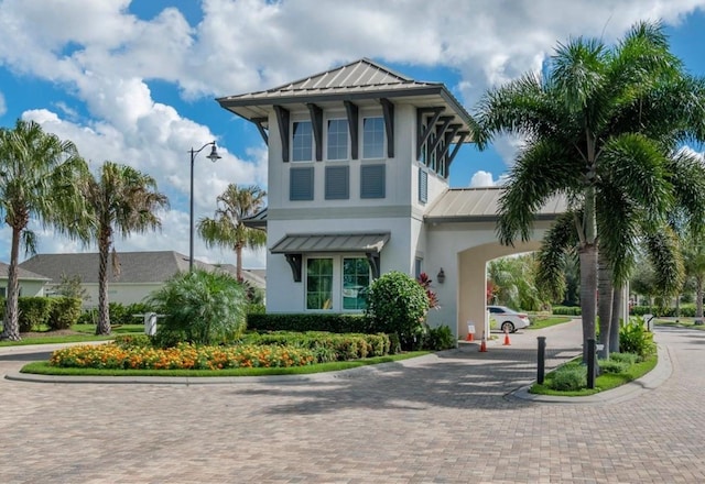 view of front facade with metal roof, decorative driveway, a standing seam roof, and stucco siding