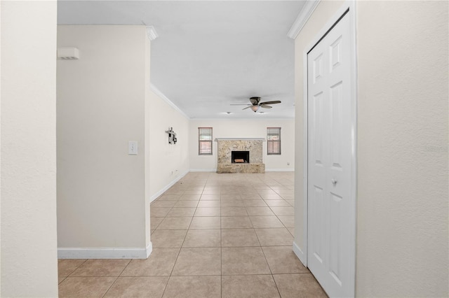 unfurnished living room featuring ceiling fan, ornamental molding, and light tile patterned floors