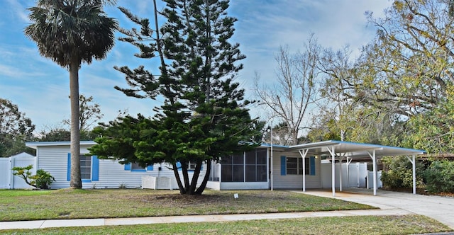 view of front facade with a carport, a sunroom, and a front yard